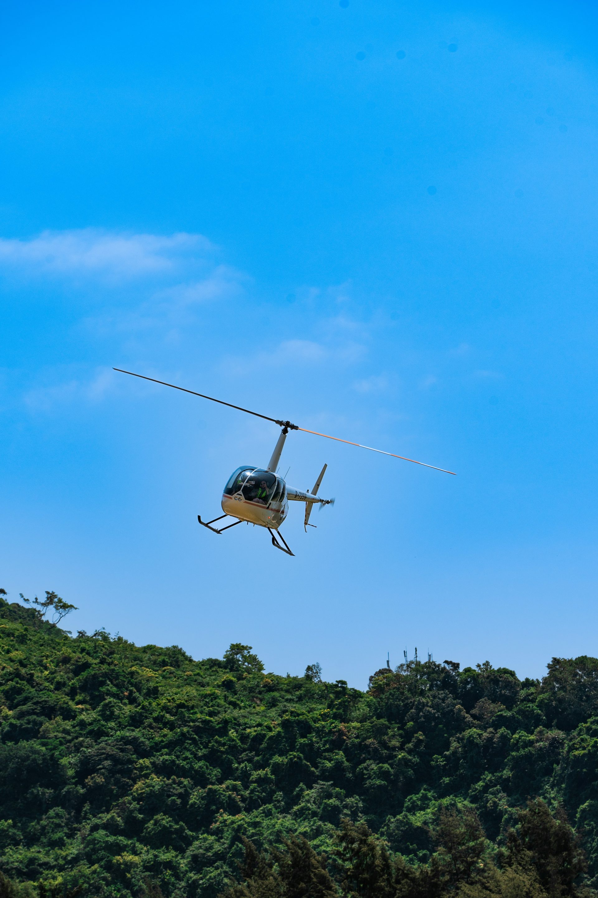 a helicopter flying over a lush green hillside